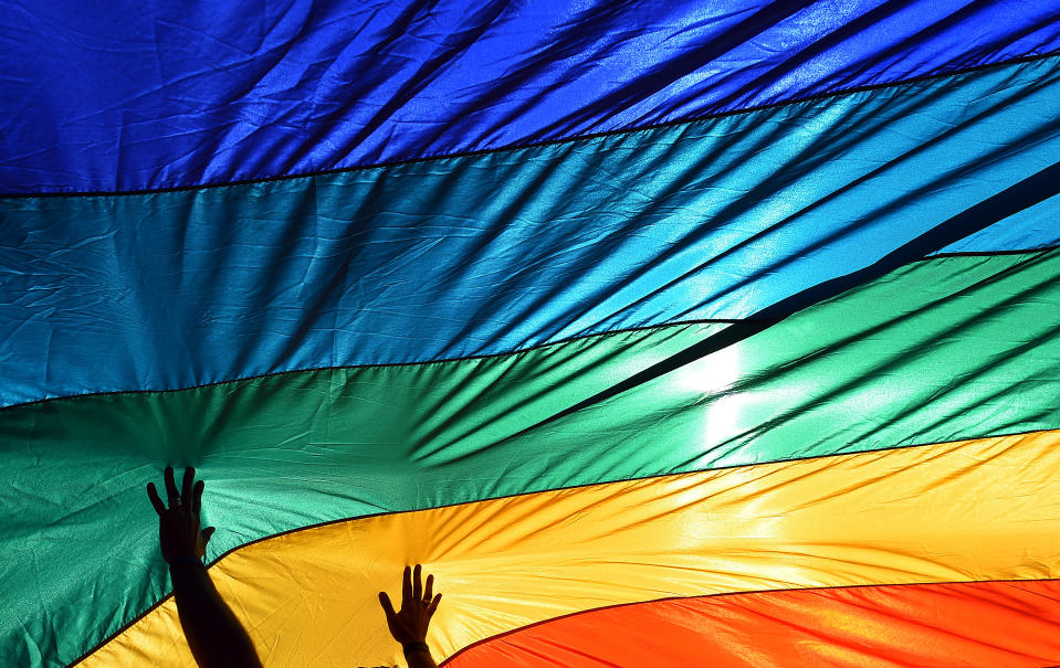 A man reaches out to a large rainbow flag which is placed in support of gay marriage in front of the U.S. Supreme Court in Washington, April 28, 2015. (Photo: Astrid Riecken For The Washington Post via Getty Images)