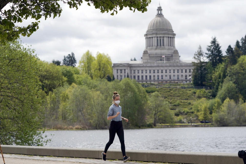 A person wears a mask while jogging, Tuesday, April 27, 2021, near the Capitol in Olympia, Wash. The Centers for Disease Control and Prevention eased its guidelines Tuesday on the wearing of masks outdoors, saying fully vaccinated Americans don't need to cover their faces anymore unless they are in a big crowd of strangers. (AP Photo/Ted S. Warren)