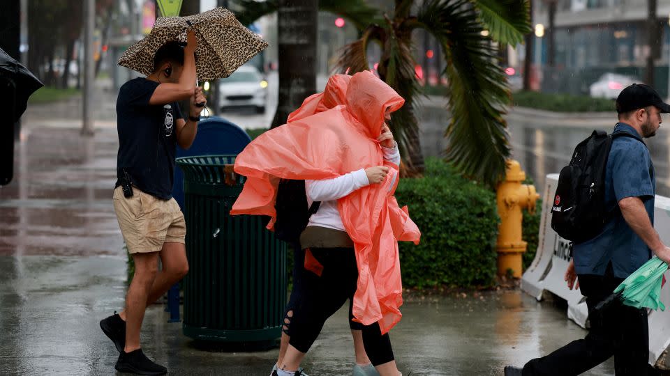 Pedestrians try to stay dry as rain inundates the area on November 15, 2023 in Miami Beach, Florida. - Joe Raedle/Getty Images