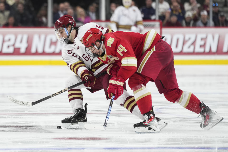 Boston College forward Ryan Leonard and Denver forward Rieger Lorenz (14) battle for the puck during the third period in the championship game of the Frozen Four NCAA college hockey tournament Saturday, April 13, 2024, in St. Paul, Minn. (AP Photo/Abbie Parr)