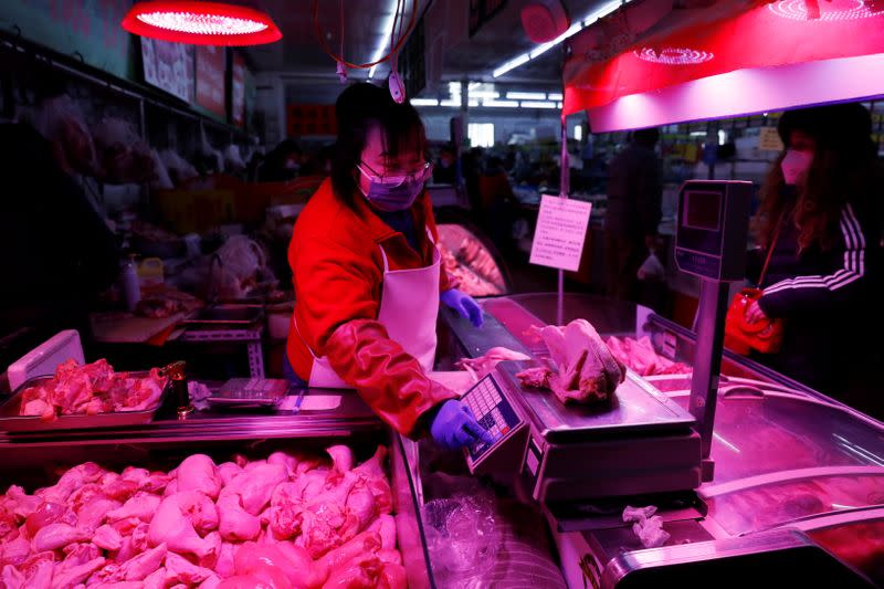Vendor weighs a chicken at a market in Beijing