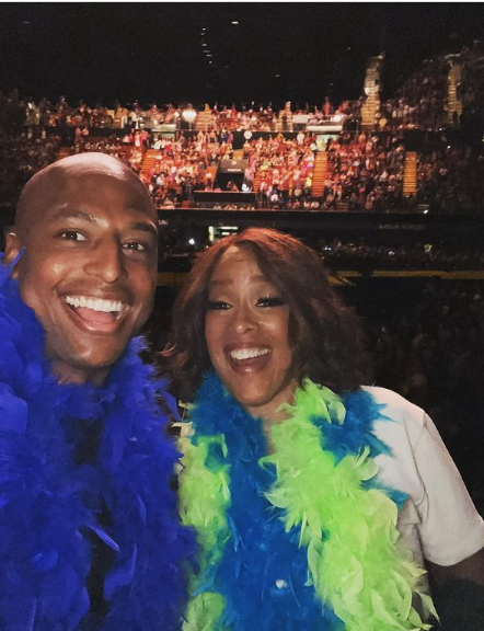 a man and woman taking a selfie in front of a large crowd