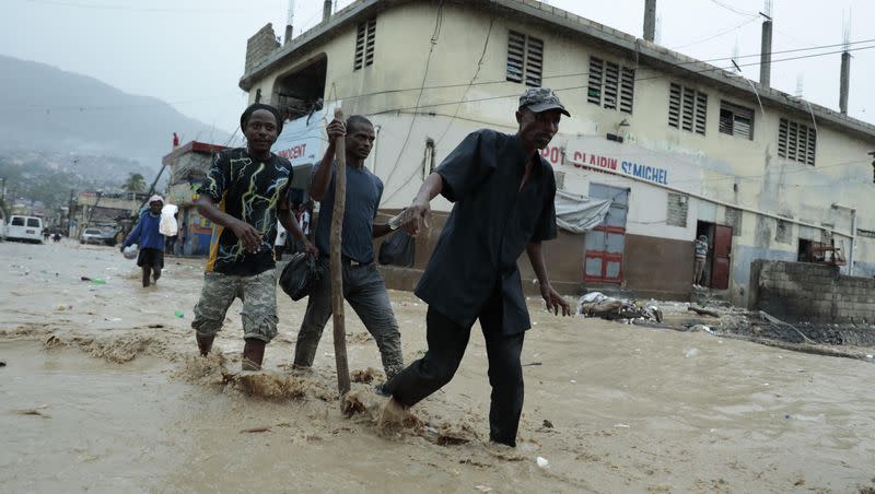 Residents wade through a flooded street after a heavy rain in Port-au-Prince, Haiti, Saturday, June 3, 2023. Nearly 13,400 people were displaced due to flooding from the storms.