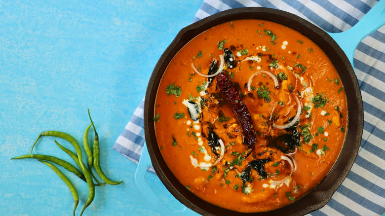 orange curry in pot on blue background