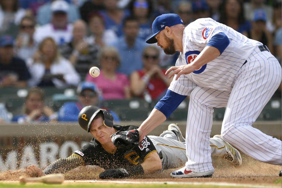 Pittsburgh Pirates' Kevin Newman left, slides safely into home plate on a throwing error by Chicago Cubs center fielder Albert Almora Jr. as Chicago Cubs starting pitcher Jon Lester right, tries to apply the tag during the first inning of a baseball game Friday, Sept. 13, 2019, in Chicago. (AP Photo/Paul Beaty)