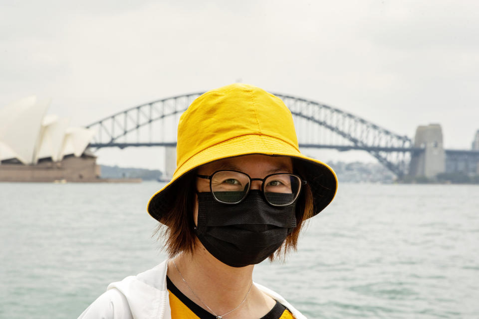 A tourist from Hong Kong is seen wearing a mask at Mrs Macquarie's Chair with the Sydney Harbour Bridge in the background.