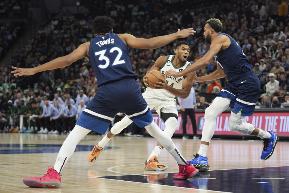 Milwaukee Bucks forward Giannis Antetokounmpo, center, works toward the basket against Minnesota Timberwolves center Karl-Anthony Towns (32) and center Rudy Gobert, right, during the first half of an NBA basketball game, Friday, Nov. 4, 2022, in Minneapolis. (AP Photo/Abbie Parr)