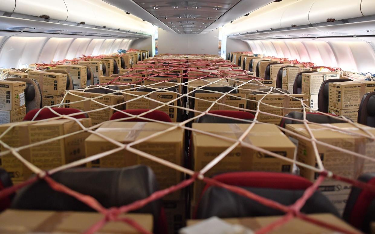 Cargo nets cover boxes of PPE disposable gloves stored on passenger seats inside the cabin of an aircraft, after it landed in southern England in 2020 - AFP