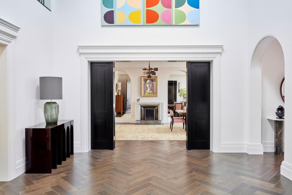 Connecting through to the dining room, the central hall is the heart of the house. Here, a console by Hervé van der Straeten and a colorful artwork by Terry Frost, a leading British abstract artist who worked in St. Ives, Cornwall, during the 1950s, reign supreme. In the dining room, the light fixture was designed by the late Irish designer David Collins for Lobmeyr.