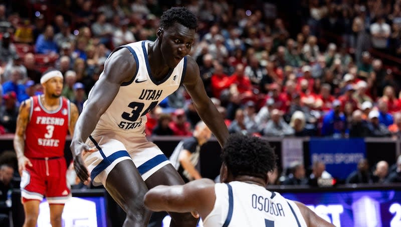 Utah State Aggies forward Kalifa Sakho (34) helps Utah State Aggies forward Great Osobor (1) up after Osobor was fouled during the game between the Utah State Aggies and the Fresno State Bulldogs in the quarterfinals of the Mountain West 2024 men's basketball championship at the Thomas & Mack Center in Las Vegas on Thursday, March 14, 2024.