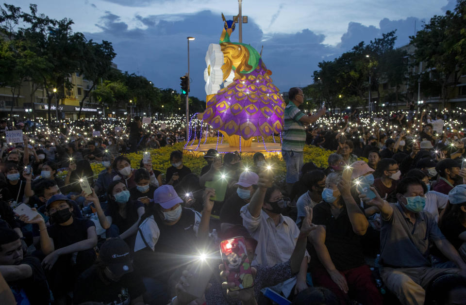 Pro-democracy activities display mobile phones with flash lights on during a protest at Democracy Monument in Bangkok, Thailand, Sunday, Aug, 16, 2020. Protesters have stepped up pressure on the government demanding to dissolve the parliament, hold new elections, amend the constitution and end intimidation of the government's opponents. (AP Photo/Gemunu Amarasinghe)