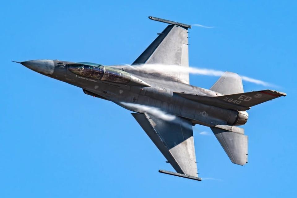 A fighter jet is surrounded by a cloud as it breaks the sound barrier.