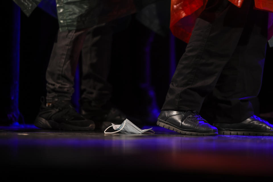 A face mask lies on the floor as inmates perform in the State of Siege, by French author Albert Camus, a play describing the arrival of plague in Spain which brings a totalitarian regime to power, at the Nottara Theatre in Bucharest, Romania, Wednesday, Nov. 24, 2021. (AP Photo/Andreea Alexandru)