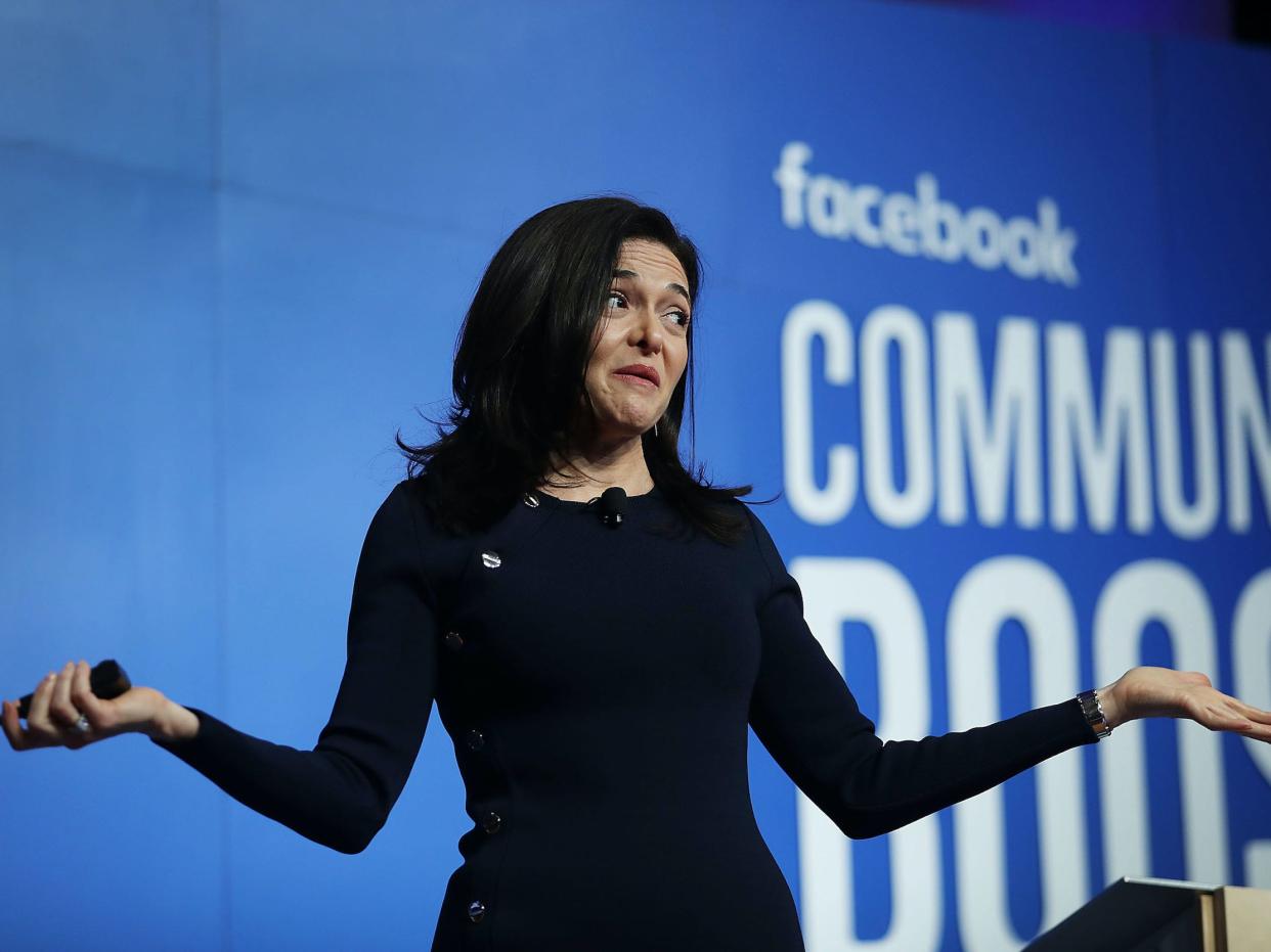 Sheryl Sandberg, Meta COO, shrugs while standing on stage at a Facebook event