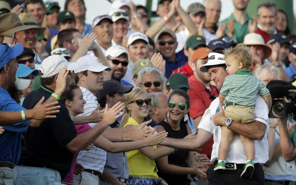 Bubba Watson, carrying his son Caleb, is congratulated by spectators after winning the Masters golf tournament Sunday, April 13, 2014, in Augusta, Ga. (AP Photo/Charlie Riedel)