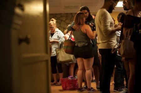 Matthew Foley embraces his girlfriend, Chloe Acerol, in a church after Acerol had been trapped inside a Trader Joe's store for three hours during a hostage situation Los Angeles, California, July 21, 2018. Acerol was in the bathroom when the suspect entered the store and was trapped in the building for roughly three hours as police cleared the scene. Foley was able to escape the building, carrying his grocery basket with him. REUTERS/Andrew Cullen