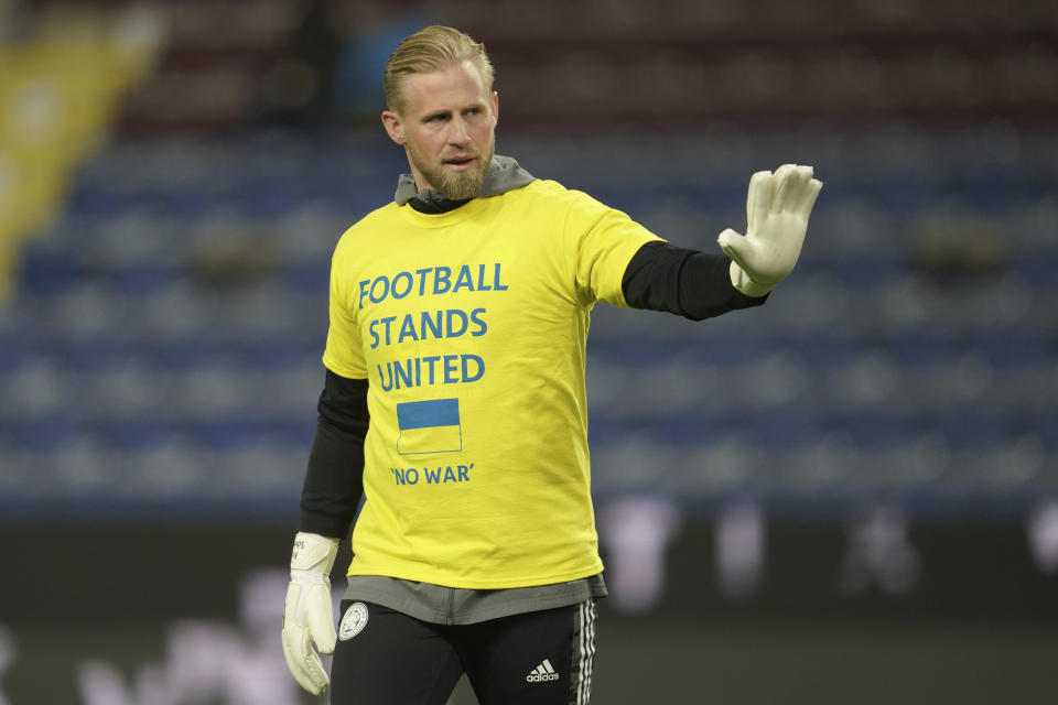 FILE - Leicester's goalkeeper and Denmark international Kasper Schmeichel wears a T-shirt, saying 'Football Stands United - No War' with the flag of Ukraine on it, as he warms up prior to the English Premier League soccer match between Burnley and Leicester City at Turf Moor stadium in Burnley, England, on March 1, 2022. The players were wearing the shirts in protest against the Russian invasion of Ukraine. One year after the invasion of Ukraine began, Russia's reintegration into the world of sports threatens to create the biggest rift in the Olympic movement since the Cold War. (AP Photo/Jon Super)