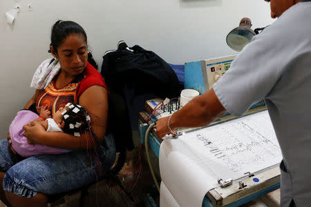 Iberis Vargas (L), holds her 7-month-old daughter, Geovelis Ramos, a neurological patient being treated with anticonvulsants, during an electroencephalogram in a clinic in La Guaira, Venezuela February 4, 2017. REUTERS/Carlos Garcia Rawlins