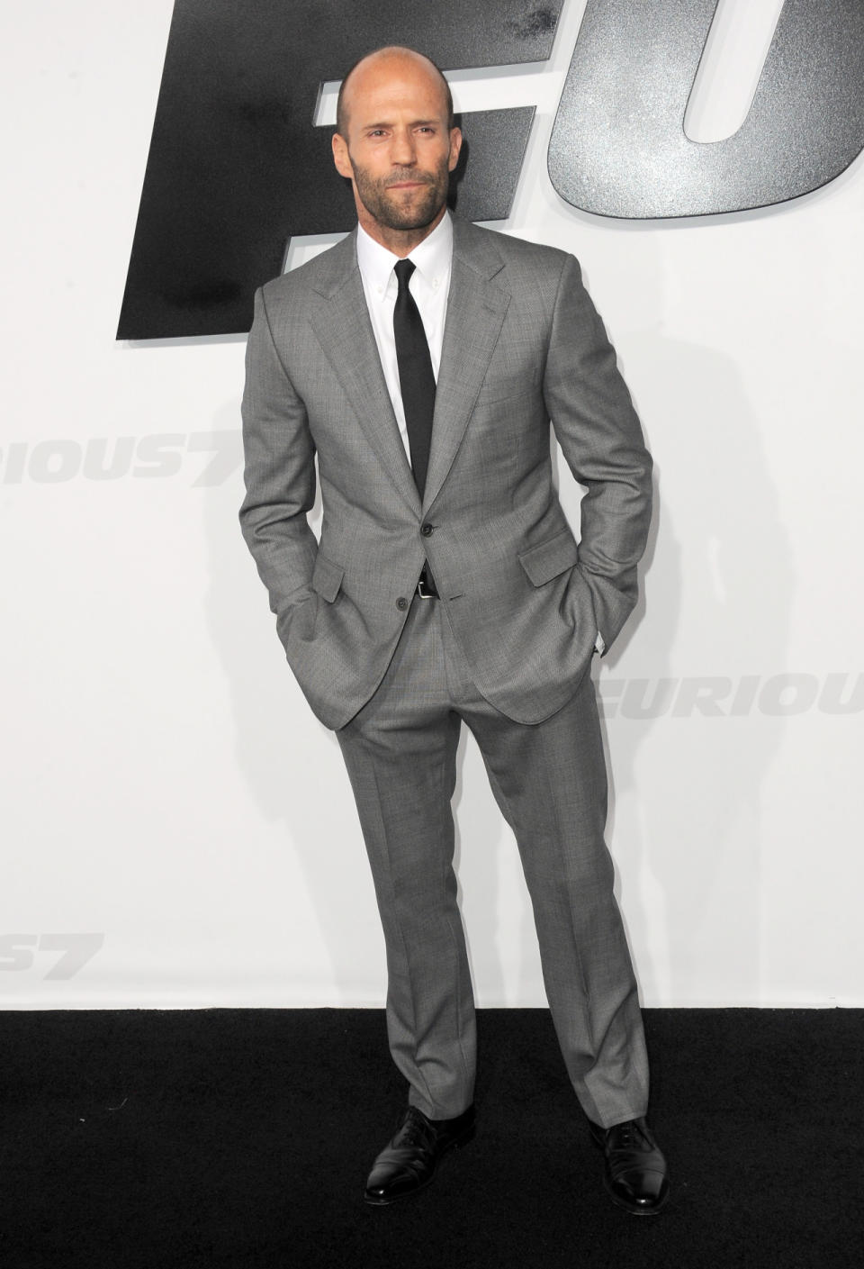 The eternal action star showed up to the “Furious 7” premiere in a gray suit and black tie that would most likely get the seal of sartorial approval from his lady love Rosie Huntington-Whiteley.