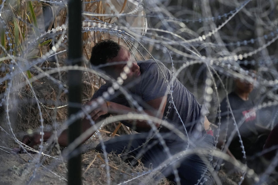 Migrants who crossed the Rio Grande from Mexico to the U.S. work their way through concertina wire, Friday, Sept. 22, 2023, in Eagle Pass, Texas. (AP Photo/Eric Gay)