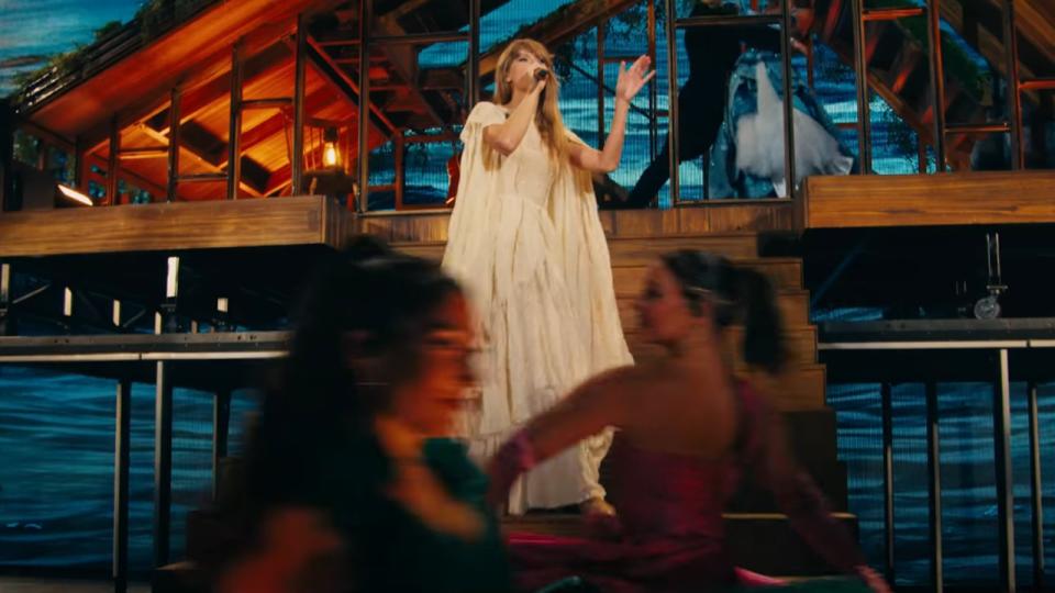 Taylor Swift sining with dancers dancing in front of her during the folklore set in the Eras Tour.