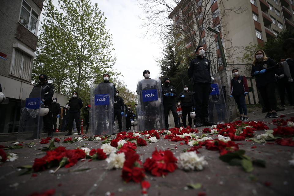 Turkish police officers, wearing face masks for protection against coronavirus, stand behind carnations left by demonstrators during May Day protests in Istanbul, Friday, May 1, 2020. Police in Istanbul detained several demonstrators who tried to march toward Istanbul’s symbolic Taksim Square in defiance of the lockdown imposed by the government due to the coronavirus outbreak. (AP Photo/Emrah Gurel)
