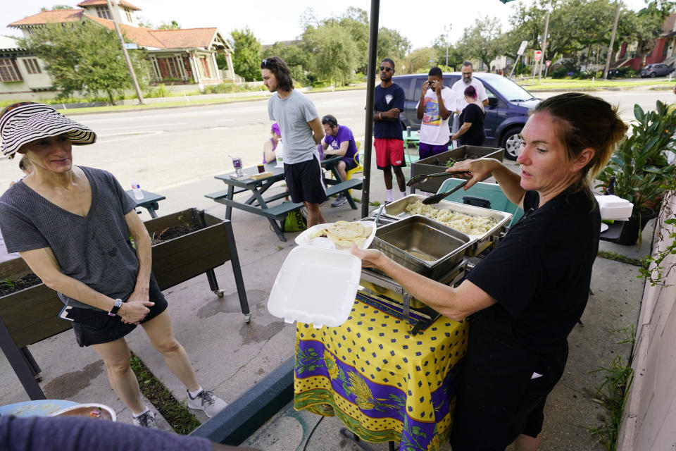 In this Wednesday, Sept. 1, 2021, photo, El Pavo Real restaurant owner Lindsey McLellan, right, used food preserved "with ice and prayer" to serve up a free steak taco meal, in New Orleans, La. In New Orleans, food is just one of the many ways that residents help each other during hard times. And it's been no different in the days after Hurricane Ida, which flooded or destroyed homes, tore up trees and knocked out the entire city's power grid.(AP Photo/Eric Gay)