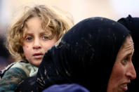 A displaced Iraqi woman who fled her home during a battle between Iraqi forces and Islamic State militants, carries her child at a checkpoint to be transfer to Hammam al-Alil camp, in Mosul, Iraq, March 20, 2017. REUTERS/Thaier Al-Sudani