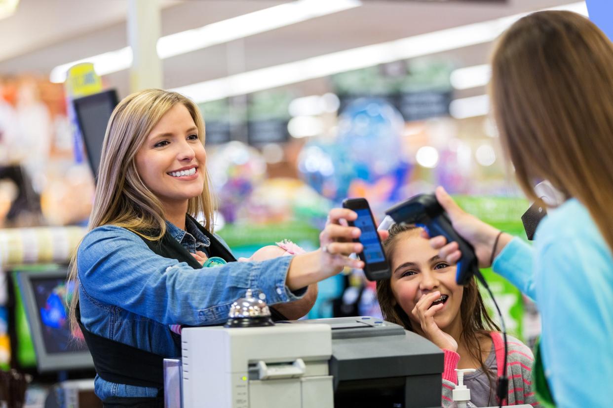 Woman showing coupons on phone at grocery store
