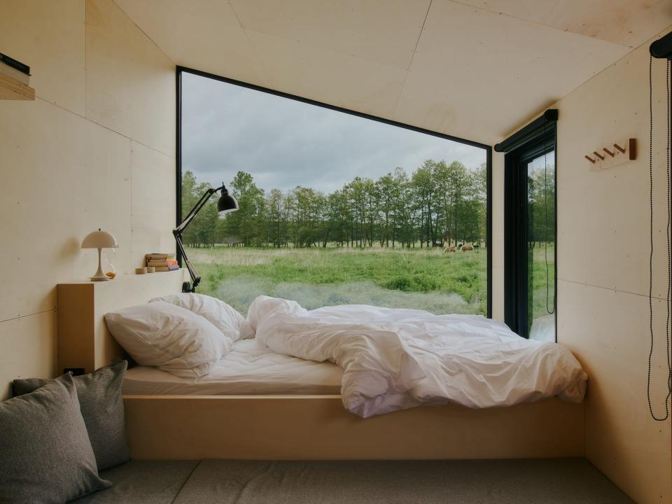 A look inside a Raus cabin with a bed near windows.