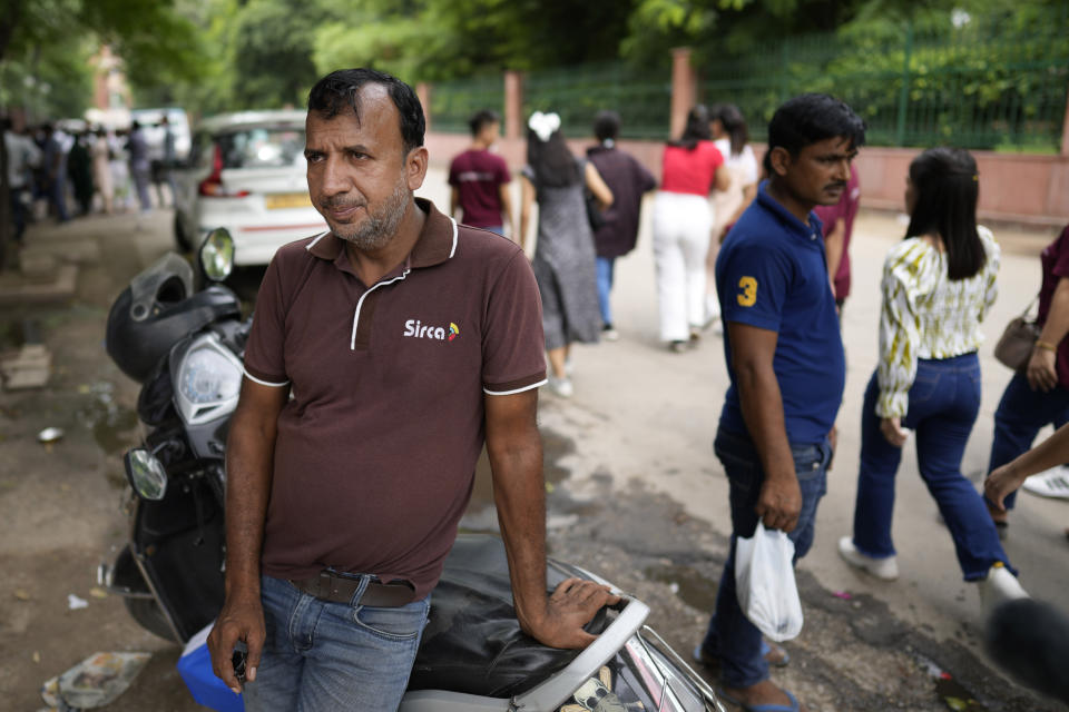 Vasim, who owns a roadside stall selling sunglasses, waits near his vehicle to spread his shop after being asked to vacate the existing place by authorities in preparation for the upcoming G20 summit, in New Delhi, India, Thursday, Aug. 24, 2023. (AP Photo/Manish Swarup)