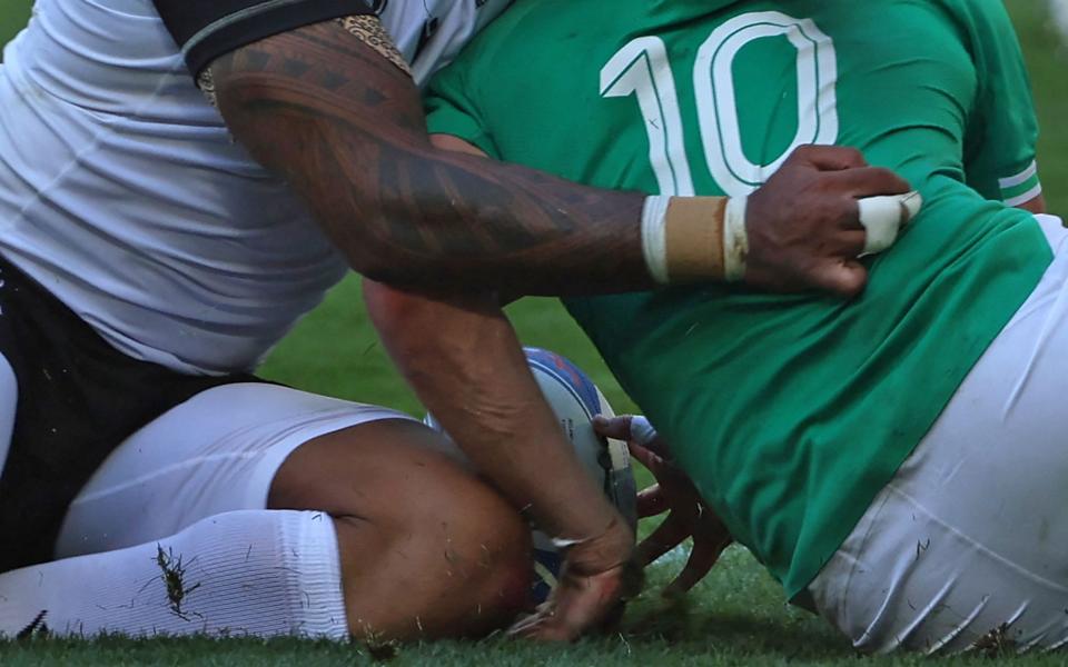 Ireland's fly-half Johnny Sexton's (R) hand bends as he is tackled by Romania's centre Jason Tomane