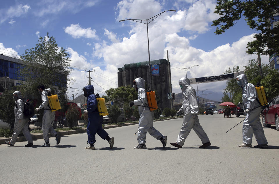 Volunteers in protective suits prepare to spray disinfectant on passing vehicles to help curb the spread of the coronavirus in Kabul, Afghanistan, Sunday, May 3, 2020. (AP Photo/Rahmat Gul)