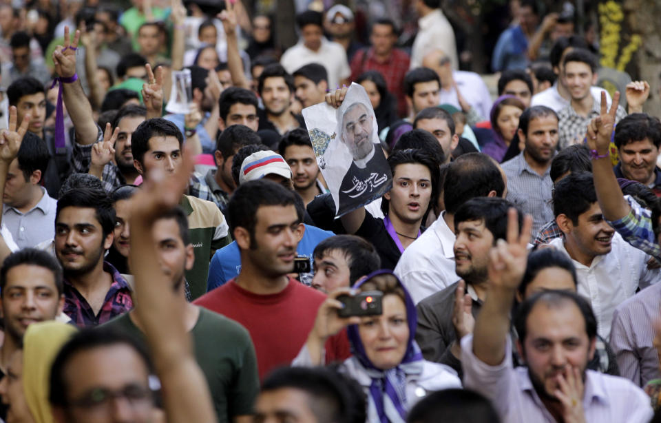 Supporters of the Iranian presidential candidate Hassan Rouhani, shown in poster at center, attend a celebration gathering in Tehran, Iran, Saturday, June 15, 2013. (AP Photo/Vahid Salemi)