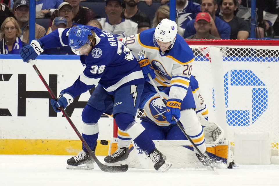 Tampa Bay Lightning left wing Brandon Hagel (38) tries to deflect the puck past Buffalo Sabres defenseman Lawrence Pilut (20) and goaltender Eric Comrie (31) during the first period of an NHL hockey game Saturday, Nov. 5, 2022, in Tampa, Fla. (AP Photo/Chris O'Meara)