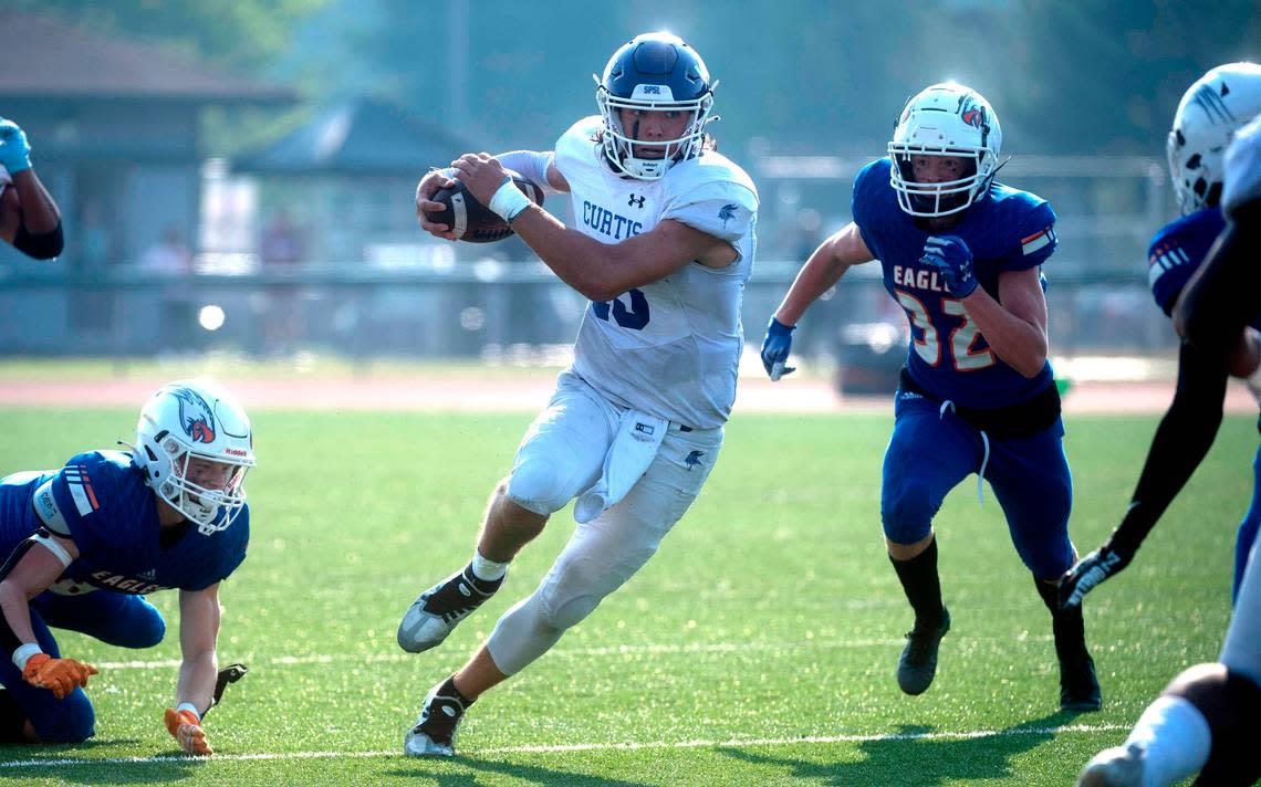 Curtis quarterback Rocco Koch scramlbes between Graham-Kapowsin defenders Ethan Pletcher (left) and Josh Massey during Saturday’s football game at Art Crate Field in Spanaway, Washington, Oct. 8, 2022. Graham-Kapowsin won the game, 24-19.