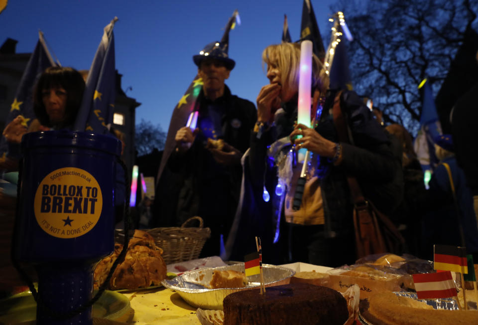 Remain in the European Union protesters eat after paying for snacks at a stall run by the campaigners to help pay for they placards and flags outside the Palace of Westminster in London, Wednesday, Feb. 27, 2019. British Prime Minister Theresa May says she will give British lawmakers a choice of approving her divorce agreement, leaving the EU March 29 without a deal or asking to delay Brexit by up to three months. (AP Photo/Alastair Grant)