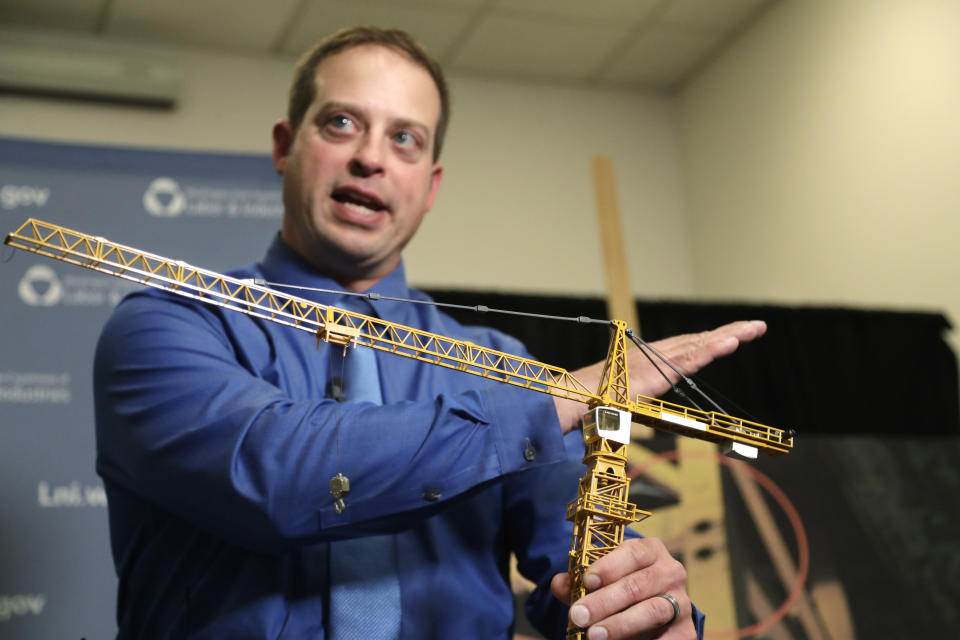 Brian Haight, crane program manager for Washington state's Department of Labor and Industries, uses a model of a crane during a news conference Thursday, Oct. 17, 2019, in Tukwila, Wash., to explain the collapse of a crane earlier in the year in Seattle that killed four. Washington State's L&I released the results of its investigation on the collapse Thursday. It found, as experts have long suspected, that the crane toppled because workers who were disassembling it had prematurely removed pins securing the sections of the crane's mast. (AP Photo/Elaine Thompson)