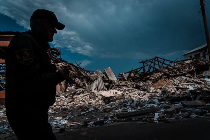 LYSYCHANSK, UKRAINE -- JUNE 13, 2022: A security guard walks by the rubble of a police station that was destroyed by bombardment, in Lysychansk, Ukraine, Monday June 13, 2022. (Marcus Yam / Los Angeles Times)