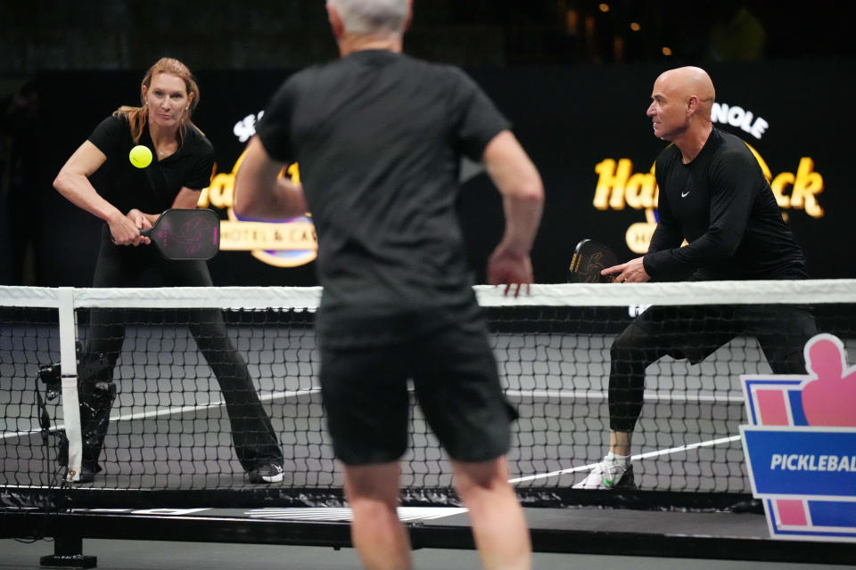 Steffi Graf returns a volley from John McEnroe as teammate Andre Agassi looks on during Pickleball Slam 2.