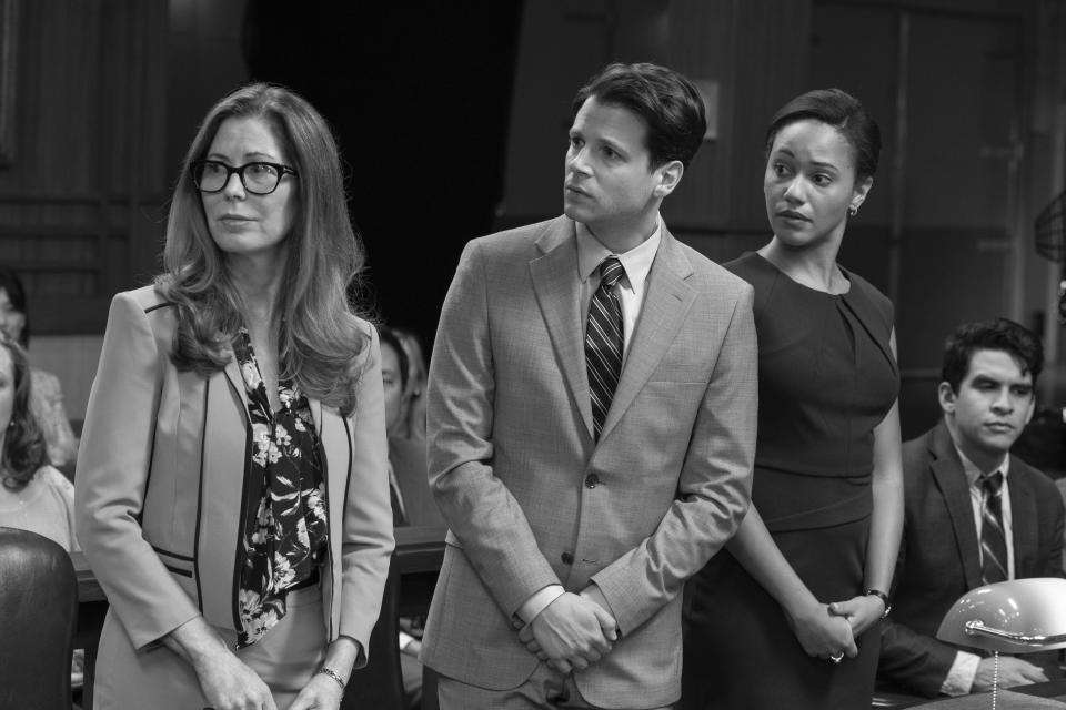 Three lawyers in a courtroom looking concerned, in black and white. 