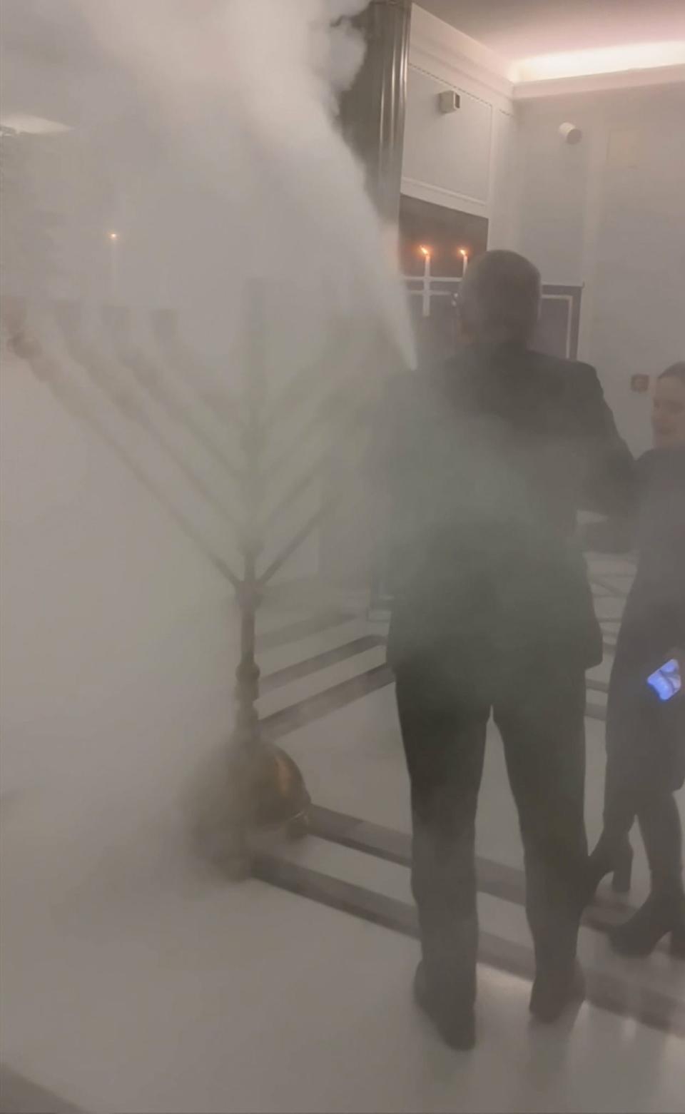 A video grab from TVN24 shows Polish ultra far-right lawmaker Grzegorz Braun from Confederation using a fire extinguisher to put out a Hanukkah menorah placed in the parliament lobby lit moments earlier during the annual Hanukkah ceremony at the Sejm in Warsaw, Tuesday.