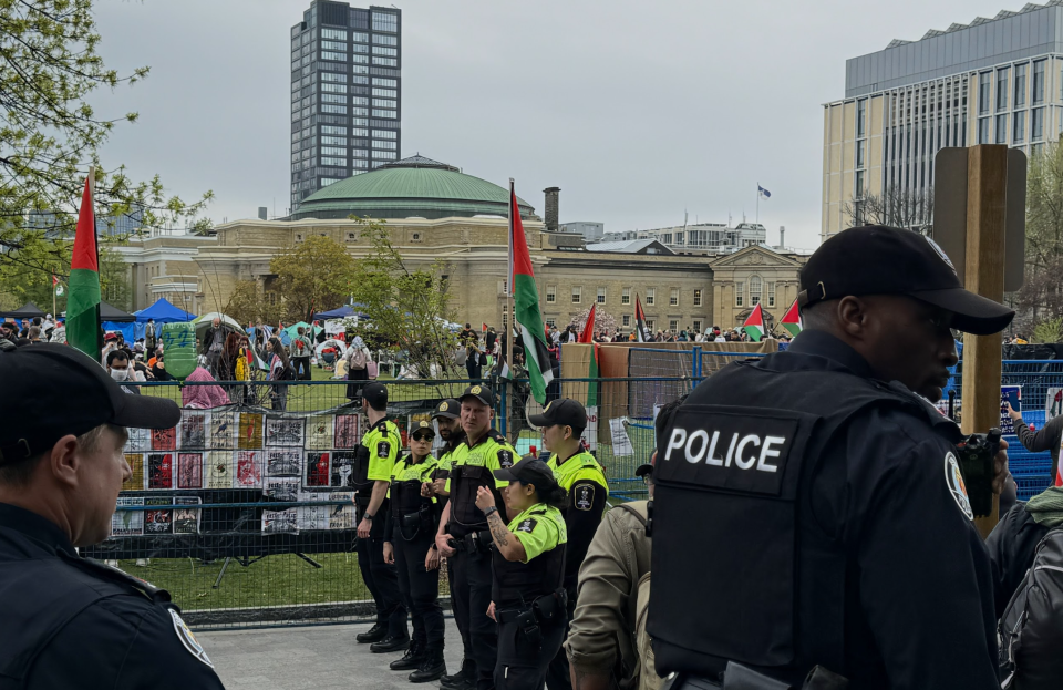 <p>Police and campus security stand near the entrance of the U of T encampment. (Credit: Corné van Hoepen)</p> 
