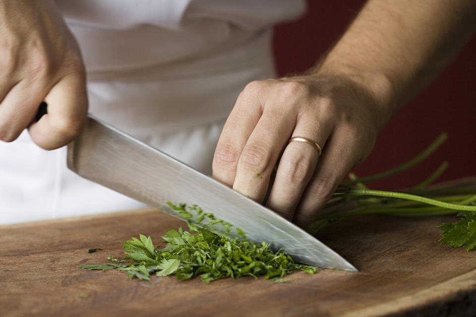 Person chopping fresh herbs on a wooden board