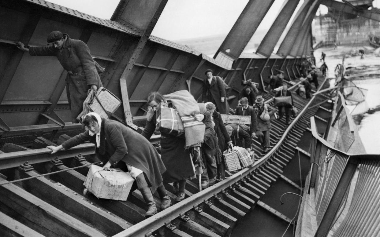 German civilians, fleeing the Soviet advance, pick their way across the River Elbe on a partially destroyed railway bridge at Tangermünde, May 1945 - IWM