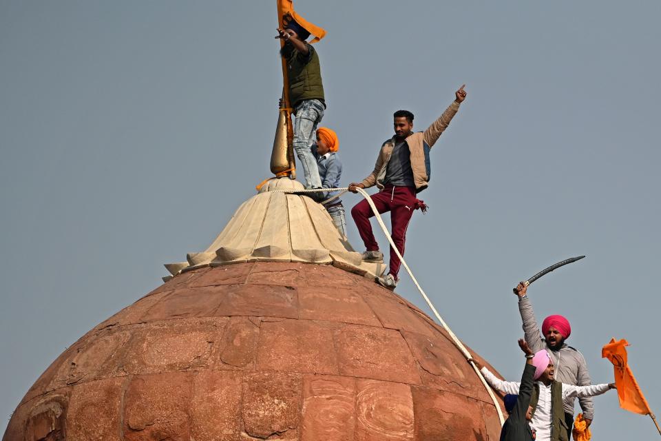 Protesters climb on a dome at the ramparts of the Red Fort as farmers continue to demonstrate against the central government's recent agricultural reforms in New Delhi on January 26, 2021. (Photo by Sajjad HUSSAIN / AFP) (Photo by SAJJAD HUSSAIN/AFP via Getty Images)