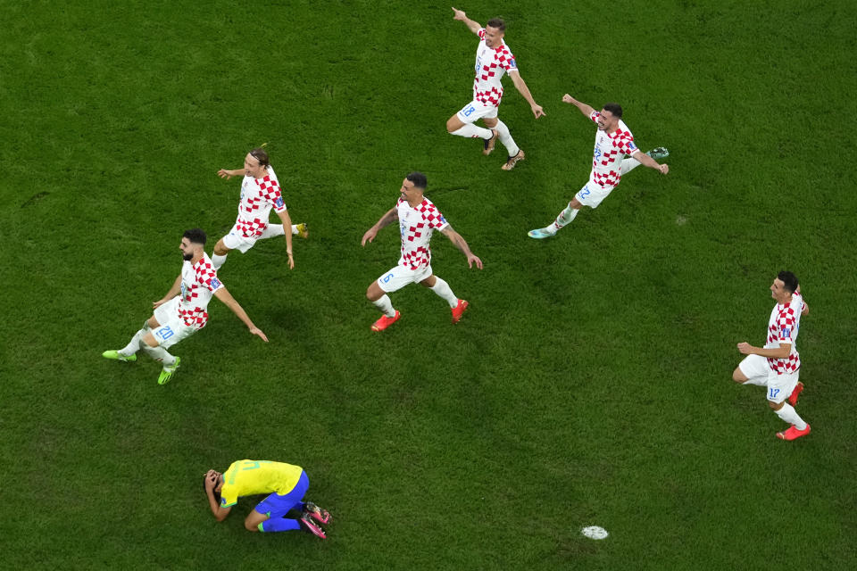 Brazil's Marquinhos is dejected after failing to score from the penalty spot as Croatia's players celebrate winning the World Cup quarterfinal soccer match between Croatia and Brazil, at the Education City Stadium in Al Rayyan, Qatar, Friday, Dec. 9, 2022. (AP Photo/Petr David Josek)