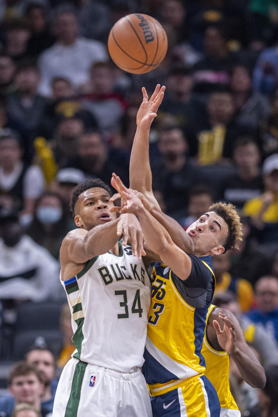 Indiana Pacers guard Chris Duarte (3) and Milwaukee Bucks forward Giannis Antetokounmpo (34) battle for the ball during the first half of an NBA basketball game in Indianapolis, Sunday, Nov. 28, 2021. (AP Photo/Doug McSchooler)