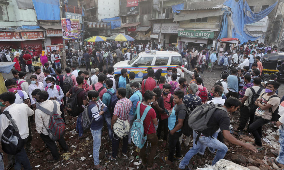 A police vehicle patrols as migrant workers wait for work in Mumbai, India, Monday, Nov. 23, 2020. India has more than 9 million cases of coronavirus, second behind the United States. (AP Photo/Rafiq Maqbool)