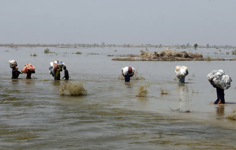 En esta imagen de archivo, víctimas de las graves inundaciones causadas por el monzón llevan ayuda a hombros en medio de la crecida, en el distrito de Qambar Shahdadkot, en la provincia de Sindh, Pakistán, el 9 de septiembre de 2022. 